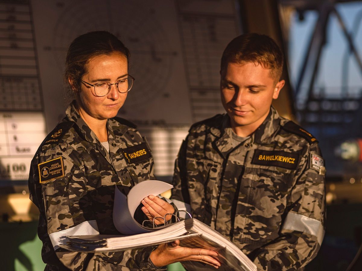 Two members of the Navy flick through the pages of a manual.