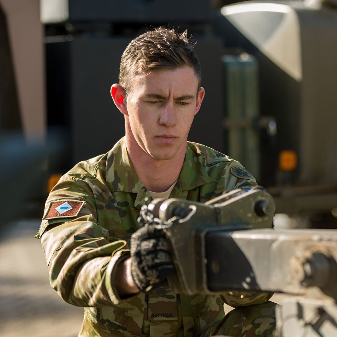 A member of the Army studies a piece of equipment.