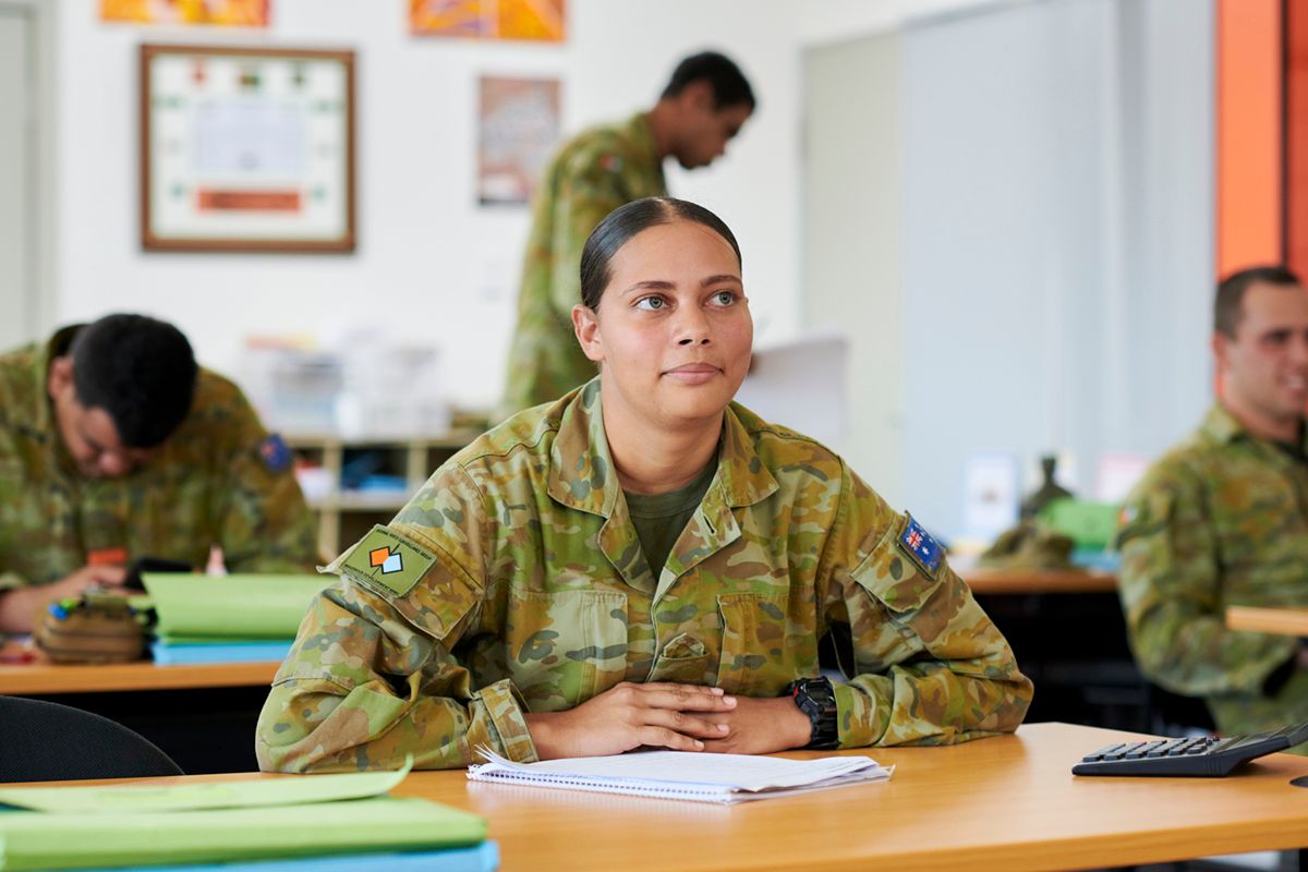 A women in uniform sits at a desk.