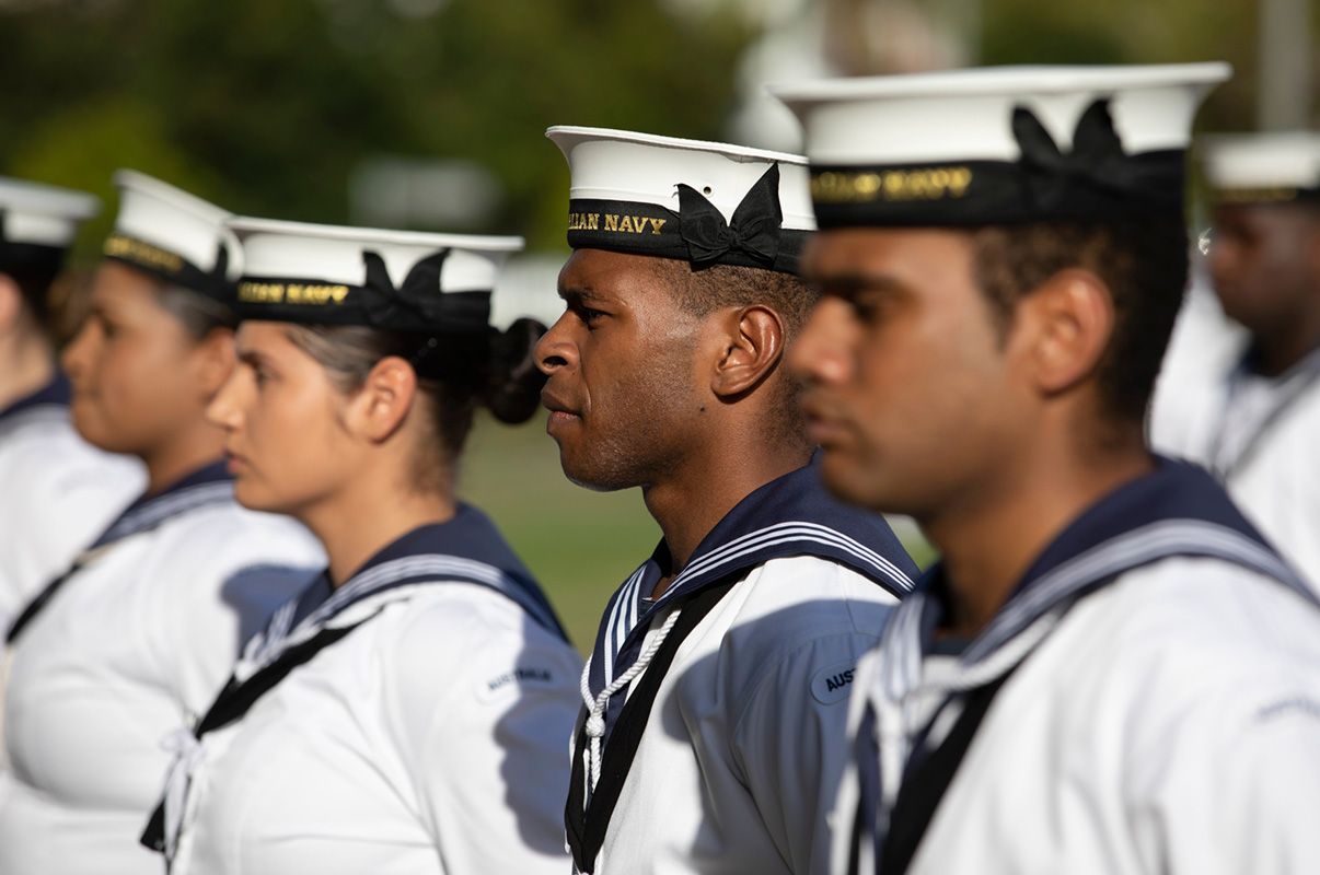 A line of sailors in uniform standing together.