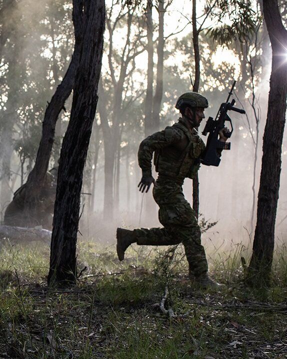 Simon is running amongst trees carrying a weapon.