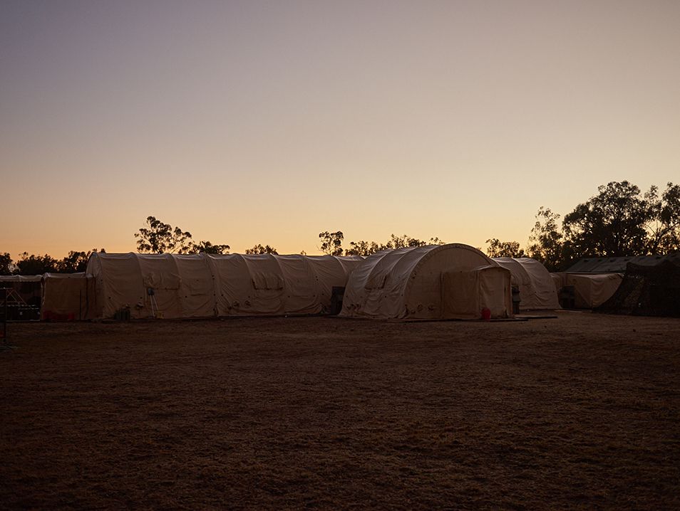 The sun rises over a row of tents in the outback.