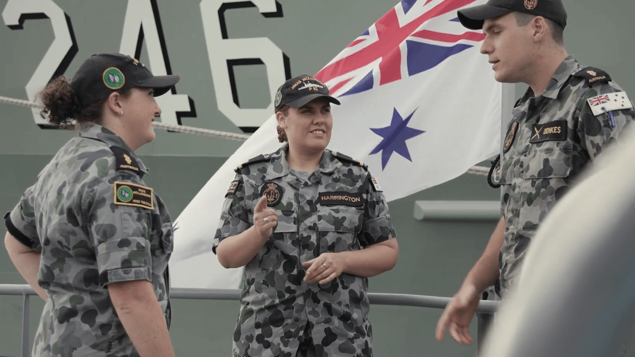 Three members of the Navy outside on a ship.