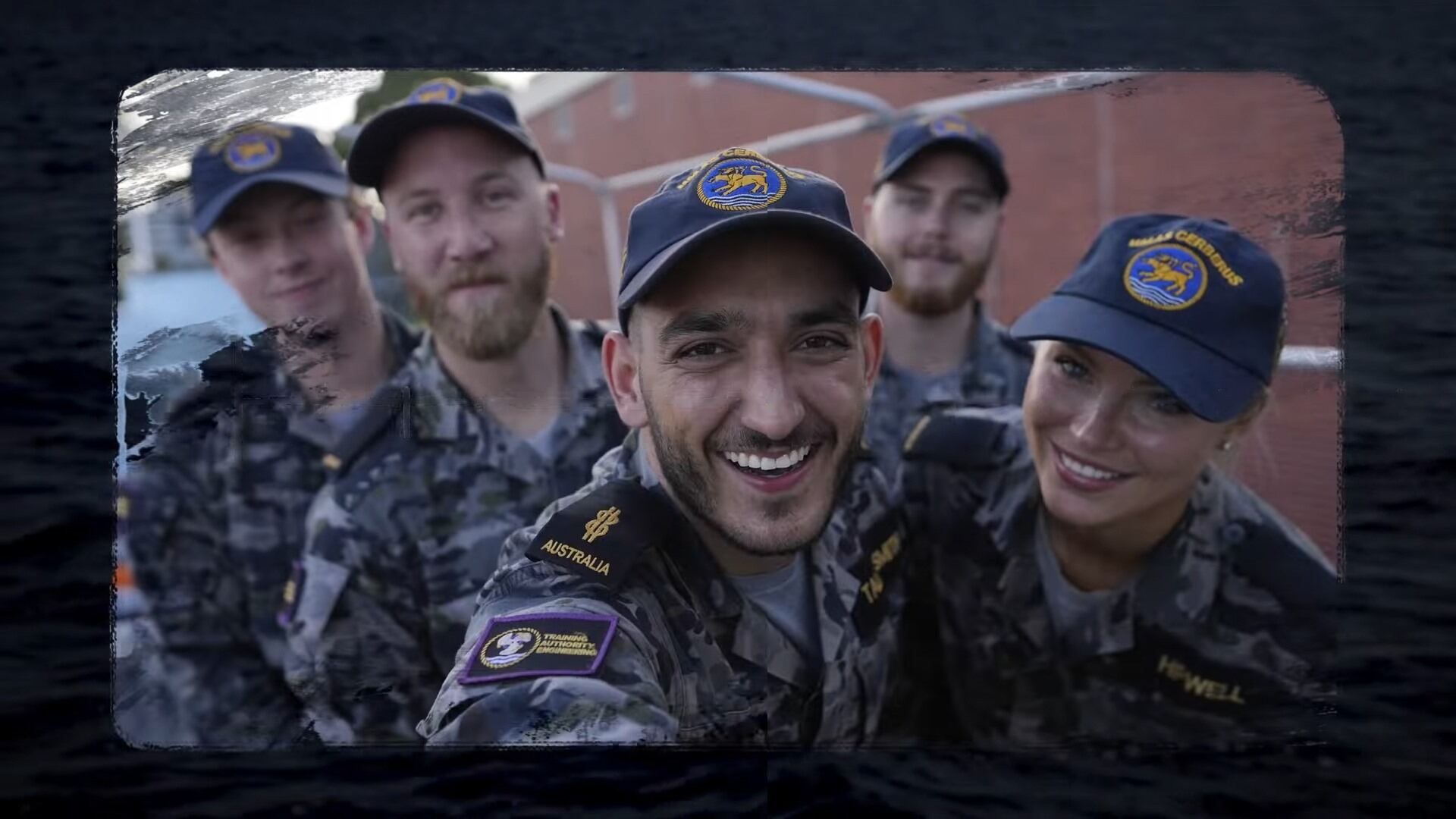 A group of Navy members standing outside smiling at the camera. 