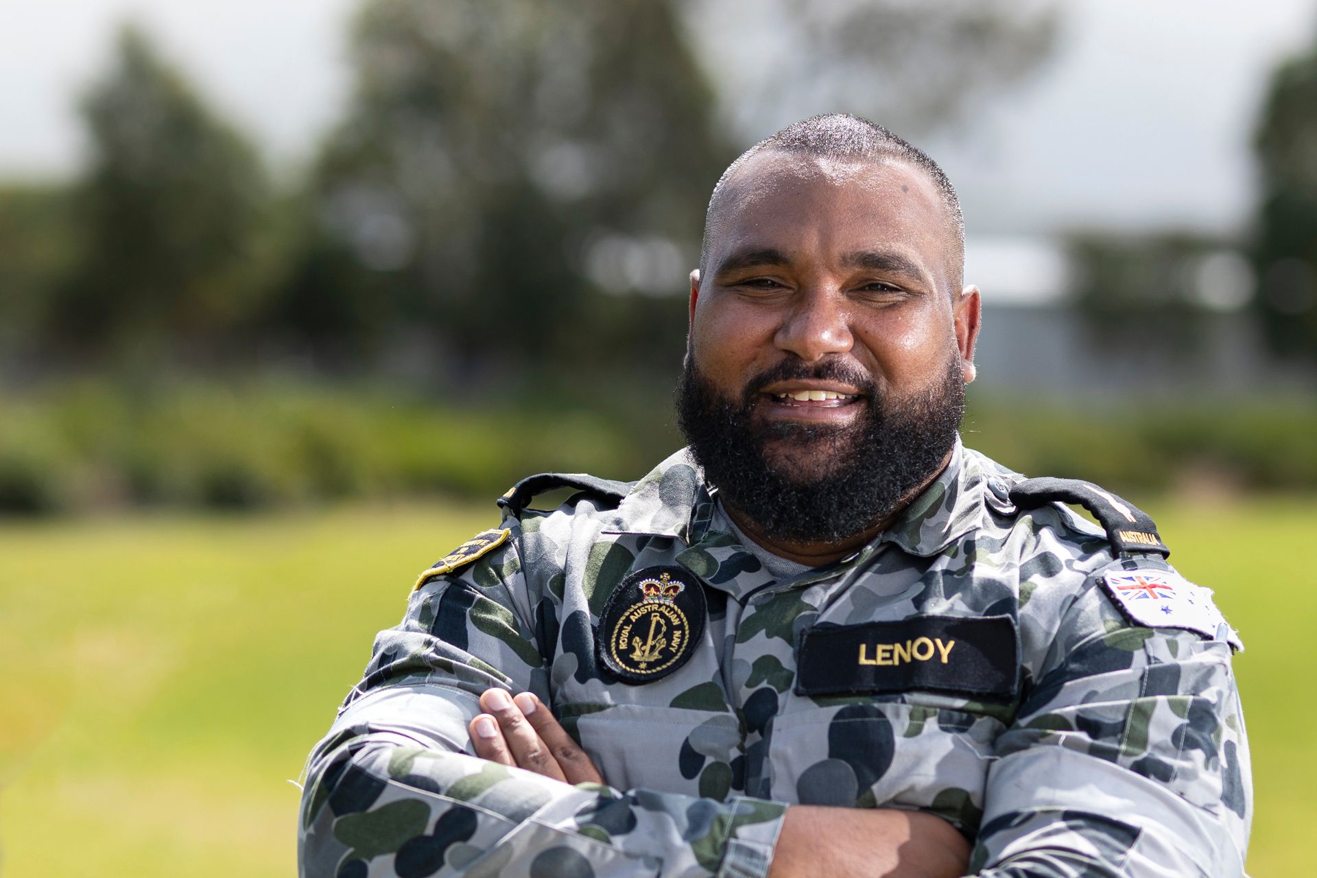 A member of the Navy in uniform smiling.