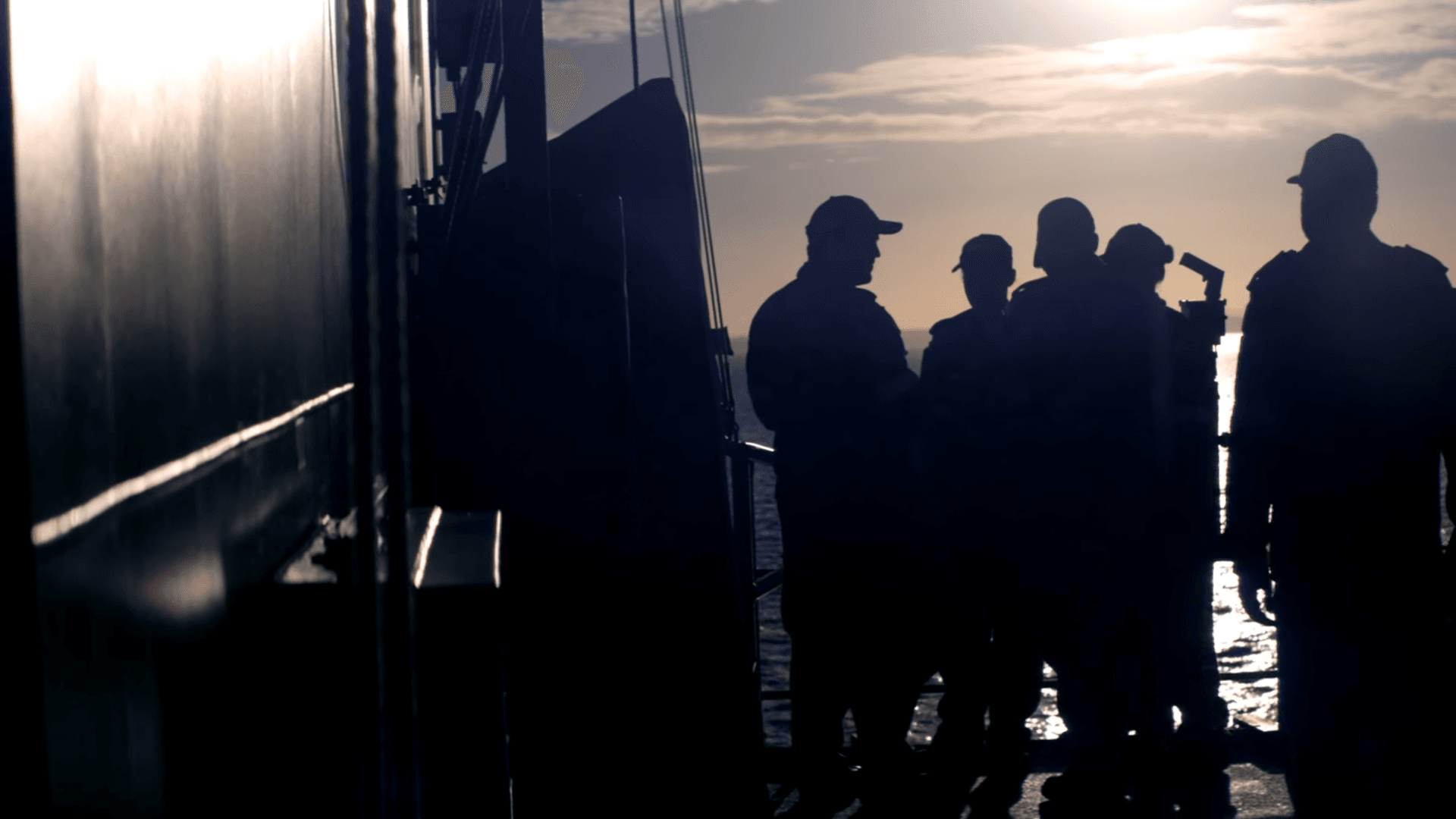 A group of members of the Navy standing outside on a ship. 