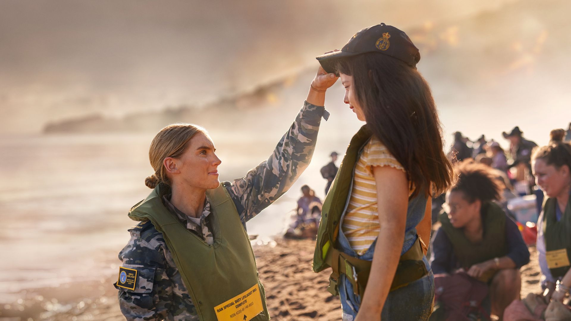 A member of the Navy outside on a beach with a young girl.