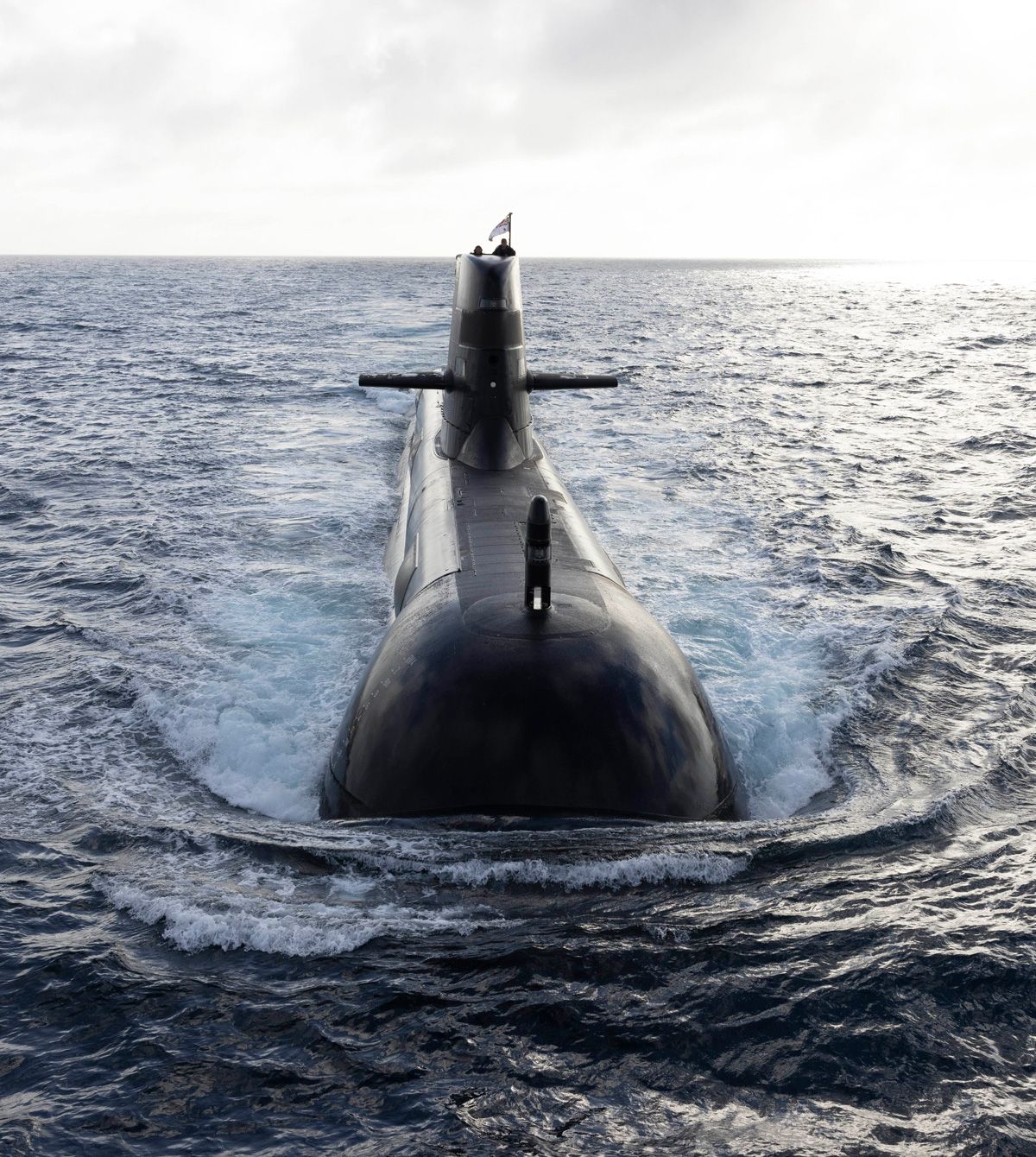 A submarine glides through the water on a sunny day, showcasing its sleek design and underwater capabilities.