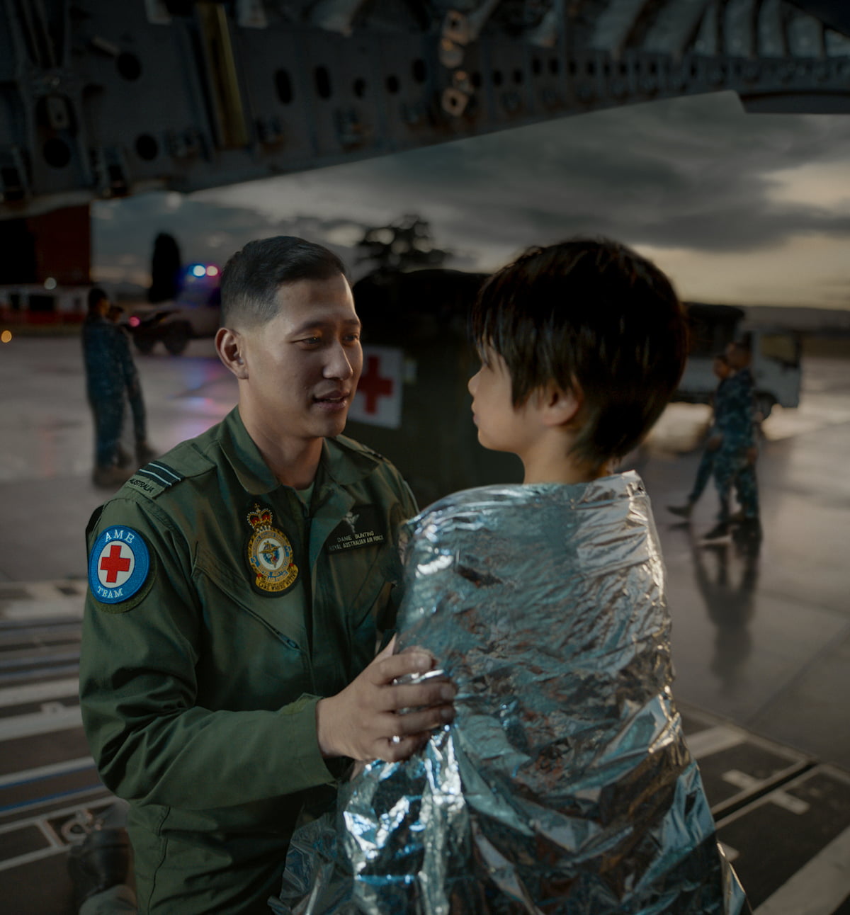 A member of the Air Force wrapping a blanket around a child.