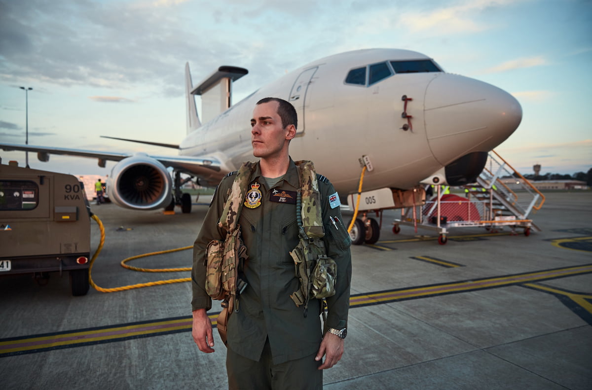 A member of the Air Force in uniform standing outside in front of an airplane.