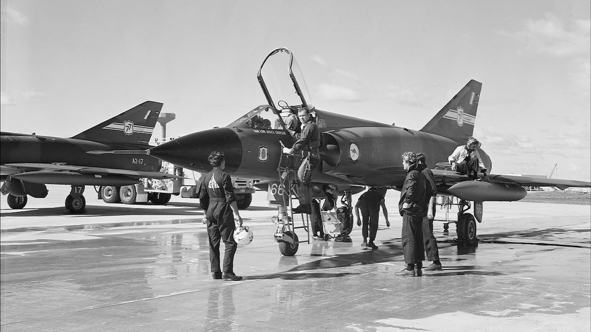 An old black and white photo  of Air Force members getting a plane ready for take off.